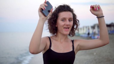 Gün batımında güneşli sahilde dans eden tatlı kız.