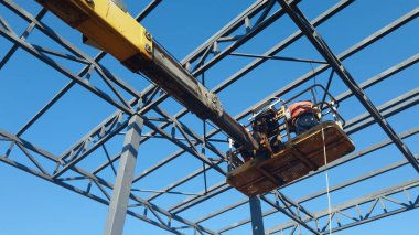 Rigger yüksek kiraz toplayıcıda. İnşaat alanının üzerinden geçiyor.