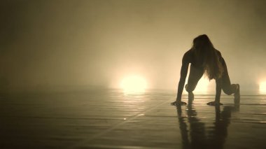 Dansçı kadın, karanlık ışıklı odada gösteri yapıyor.