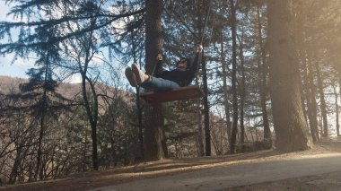 Güzel esmer ağaçta sallanıyor, ormanda sallanıyor, ağır çekimde.