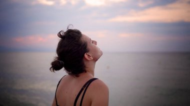 Sakin bir kadın kumsalda tek başına duruyor, üzgün ve düşünceli, sinematik çekim.