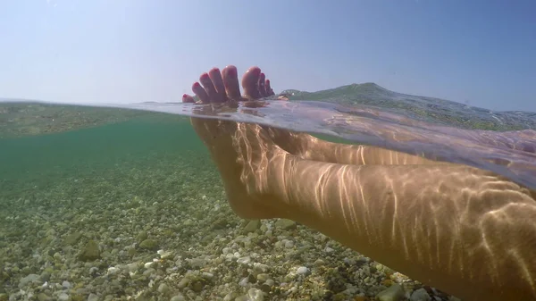 海の浅い水の中に浮かぶ女性の足 夏休みのコンセプト 半分水中ビューGoproドームショットリラックス — ストック写真