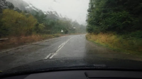 开车通过挡风玻璃与雨滴开车在山路沥青路面上 — 图库照片