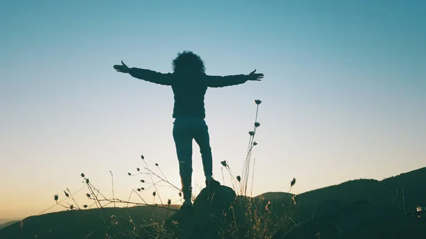 成功的概念 在美丽的夕阳西下 远足的女人在山顶上伸出手来 把美丽的夕阳西下的阳光照在她的轮廓上 — 图库照片