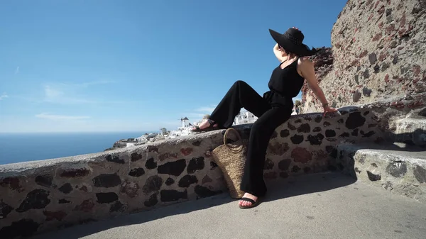 Preto Vestido Mulher Elegante Santorini Sentado Borda Parede Castelo Olhando — Fotografia de Stock