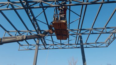 Rigger yüksek kiraz toplayıcıda. İnşaat alanının üzerinden geçiyor.