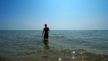 Yakışıklı sporcu erkek, deniz sahilinde sudan çıkıyor. Sinema filmi gibi.