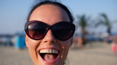 Kameraya gülümseyen ve onunla kumsalda dönen bir kızın portresi.