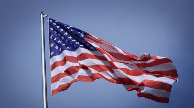 Mavi gökyüzü ve beyaz bulut önünde dalgalanan büyük Amerikan bayrağına yakın çekim. Amerikan Bayrak Dalgası. Amerikan bayrağının dalgalanmasını kapat