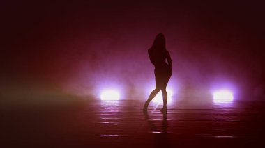 Dansçı kadın karanlıkta şehvetli hareketler sergiliyor.