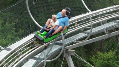 Bansko, Bulgaristan - 20 Ağustos 2019: Erkek ve kız yaz eğlence treni yolculuğunun tadını çıkarıyorlar. Kırmızı bir lunaparkta heyecanlı bir yolculuktan zevk alırken komik bir ifadeleri vardır.