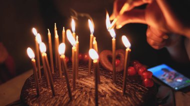 Çikolatalı pastada doğum günü mumu yakan kadın.