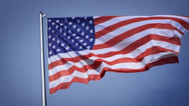 Mavi gökyüzü ve beyaz bulut önünde dalgalanan büyük Amerikan bayrağına yakın çekim. Amerikan Bayrak Dalgası. Amerikan bayrağının dalgalanmasını kapat