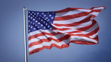Mavi gökyüzü ve beyaz bulut önünde dalgalanan büyük Amerikan bayrağına yakın çekim. Amerikan Bayrak Dalgası. Amerikan bayrağının dalgalanmasını kapat