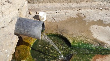 Doğal bir pınar taşradaki bir borudan akar.