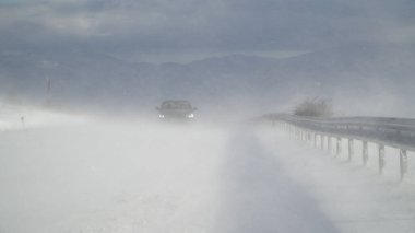 Tehlikeli bir kır yolu boyunca yoğun bir kar fırtınasının içinden geçen SUV servis aracı kar yağışı yapıyor.