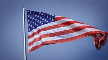 Mavi gökyüzü ve beyaz bulut önünde dalgalanan büyük Amerikan bayrağına yakın çekim. Amerikan Bayrak Dalgası. Amerikan bayrağının dalgalanmasını kapat