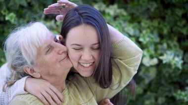 Gülümseyen bir kadının portresi. Büyükanneyi kucaklayan ve öpen. Ağır çekimde. Aile kavramı