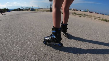 Deniz kenarında güneşli bir günde etekli paten kayan bir genç.