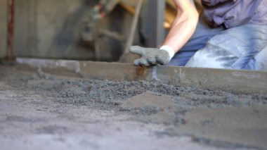 Bir inşaat işçisi çimento ve beton döküyor. Foreman yola yeni beton döktü.