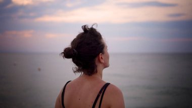 Sakin bir kadın kumsalda tek başına duruyor, üzgün ve düşünceli, sinematik çekim.