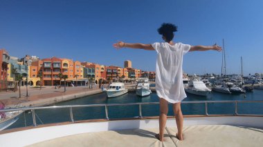 Lüks yat güvertesinde duran beyaz elbiseli manken kadın. Hurghada, Mısır 'daki iskelenin panoramik manzarası