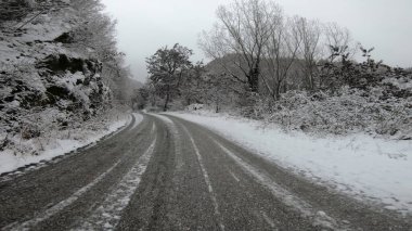 Genç sağlıklı sporcu karlı dağ yolunda asfalt yolda koşuyor.