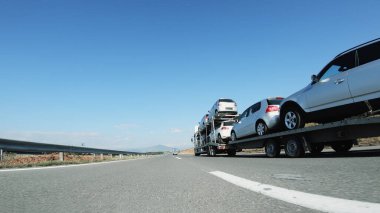 Büyük bir kamyon / araba taşıyıcısı otoyolda kullanılmış araba dağıtıyor.