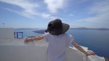 Fira, Santorini, Yunanistan 'daki Fira kilisesinin üç çanı yakınında esmer bir kadın.