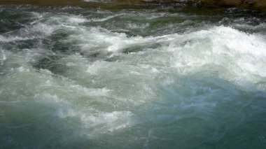 Dağ nehri kayaların arasında hızla akıyor, rafting için mükemmel. 