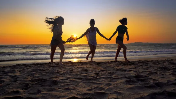 夕暮れ時にビーチを走るのを楽しんでいる女性の友人のグループ 映画のような定常撮影 — ストック写真