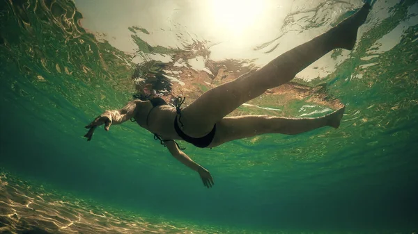 セクシーな女性でビキニリラックス上の海水面バックライトによって夏の太陽光線 水中ビュー — ストック写真