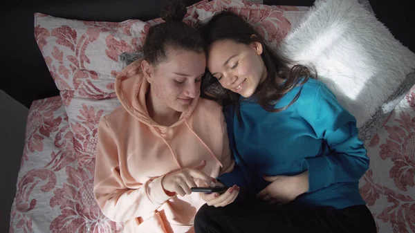 Duas Irmãs Sorridentes Felizes Estão Deitadas Cama Usando Smartphone Fazendo — Fotografia de Stock