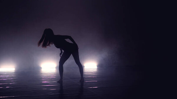 Young beautiful contemporary ballerina on smoke stage dancing modern ballet