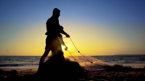 日落时在海岸拉网捕鱼的传统渔民的轮廓 — 图库照片