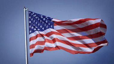 Mavi gökyüzü ve beyaz bulut önünde dalgalanan büyük Amerikan bayrağına yakın çekim. Amerikan Bayrak Dalgası. Amerikan bayrağının dalgalanmasını kapat