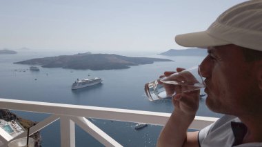 Fira, Santorini manzaralı lüks otel kafesinde yaz tatilinin tadını çıkaran bir adam. Avrupa 'ya seyahat. Turist yaşam tarzı.