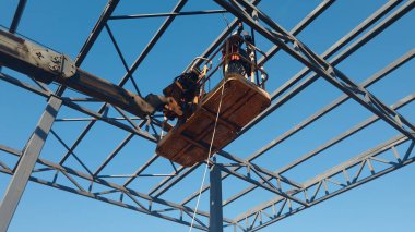 Rigger yüksek kiraz toplayıcıda. İnşaat alanının üzerinden geçiyor.