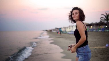 Gün batımında güneşli sahilde dans eden tatlı kız.