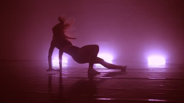 Genç, havalı bir kadın, kulüpte ışıklarla erotik danslar yapıyor.
