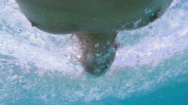 Genç adam denizde sürünüyor, sualtı manzaralı.