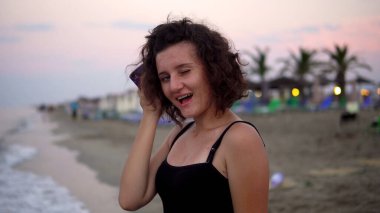 Gün batımında güneşli sahilde dans eden tatlı kız.