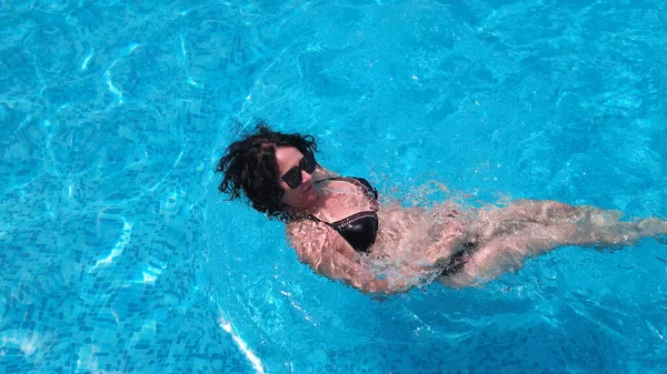卷发女子在豪华游泳池游泳 动作缓慢 — 图库照片