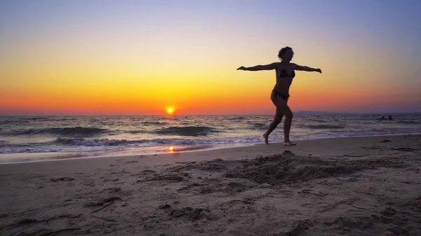 ファッションモデルの女性は 手を広く開いて海の夕日の水に歩く Freedomコンセプト 定常映画撮影 — ストック写真