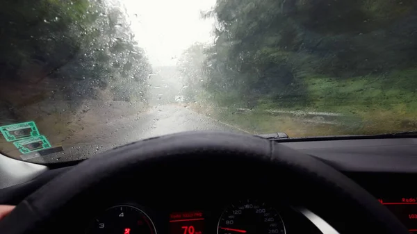 山のアスファルトの道路を運転雨滴と車のフロントガラスを介して運転Pov — ストック写真