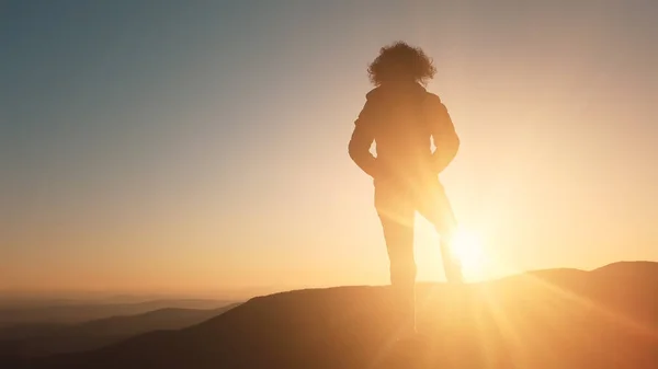 成功的概念 在美丽的夕阳西下 远足的女人在山顶上伸出手来 把美丽的夕阳西下的阳光照在她的轮廓上 — 图库照片