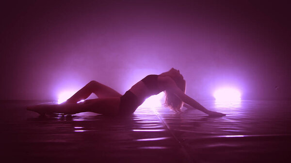 Concept. Flexible girl dancing in cloud of smoke