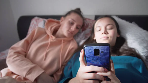Dos Hermanas Sonrientes Felices Están Acostadas Cama Usando Teléfono Inteligente —  Fotos de Stock