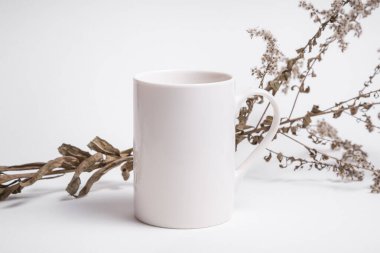 Kurumuş çimenle süslenmiş beyaz porselen kahve fincanı.