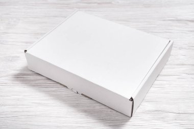 Tahta masadaki beyaz karton kutu, düz uzan. 